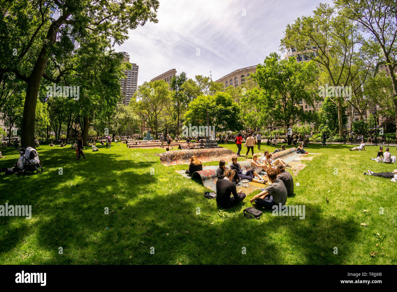 Visitors to Madison Square Park enjoy the warm weather by lounging on the sculpture “City in the Grass” by the artist Leonardo Drew on a warm Tuesday, June 4, 2019. The monumental public art commission presents a stylized cityscape over 100 feet long and provides an experiential activity, relaxing and lounging. The work will be on view and available for seating until December 15, 2019. (© Richard B. Levine) Stock Photo