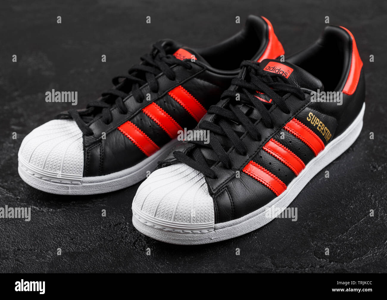 LONDON, UK - JUNE 05, 2019: Adidas Originals Superstar black shoes with red  stripes on black background Stock Photo - Alamy