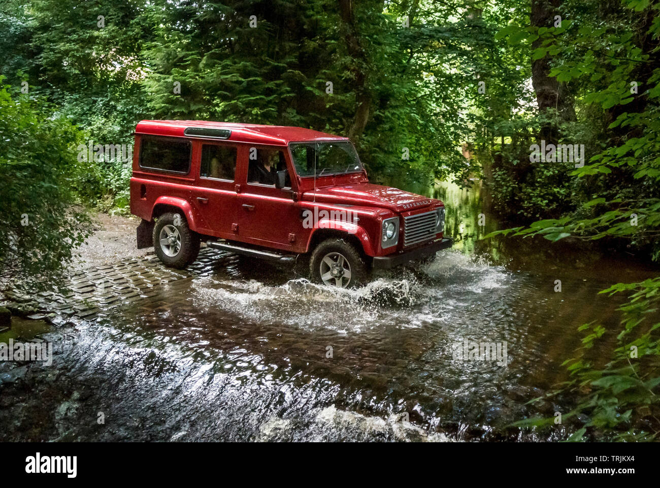 Red Land Rover Defender 110 4WD car navigating a Ford on a Green Lane track, North Yorkshire Moors, UK. Stock Photo