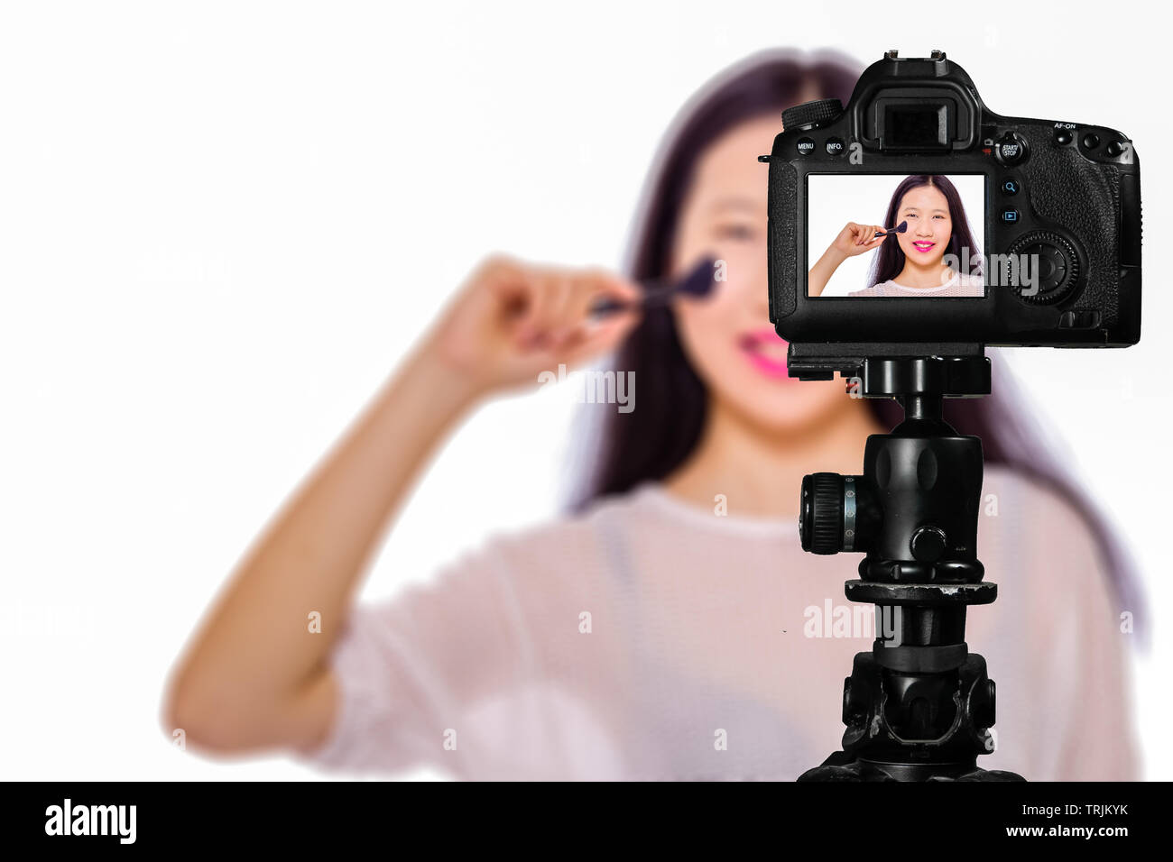 Focus on live view on camera on tripod, teenage girl  using cosmetics image on back screen with blurred scene in background. Teenage vlogger livestrea Stock Photo