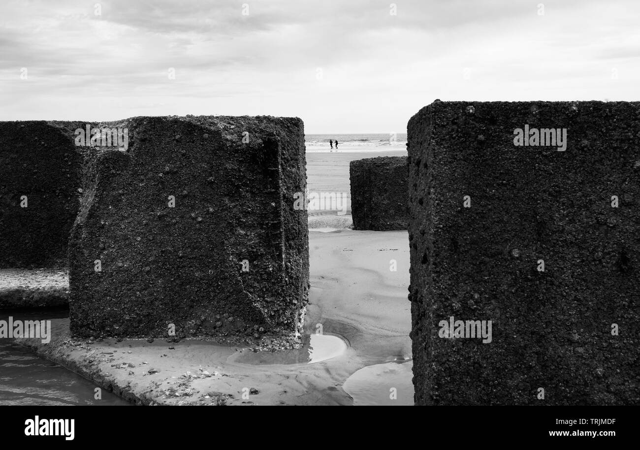 Concrete boulders used as sea defenses during World War 2 lodged in sand on beach at low tide on bright morning, Fraisthorpe, Yorkshire, UK. Stock Photo