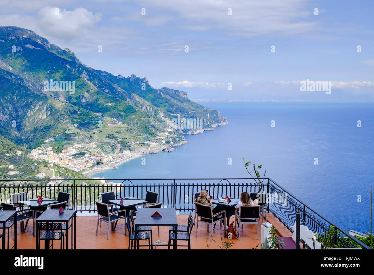 Restaurant offering outdoor dining or drinks with a view  two woman tourists relax on a cafe terrace high above the Amalfi Coast in Ravello Stock Photo