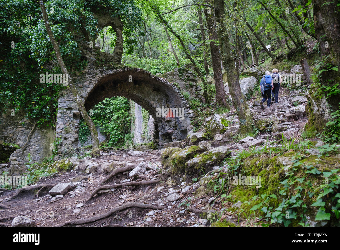 Walkers on trail past ruins  in Vallone delle Ferriere - Valley of the Iron Works also known as  Vallone dei Mulini Valley of the Papermills  Amalfi Stock Photo