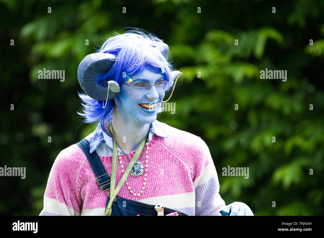 NEC, BIRMINGHAM, UK - JUNE 1, 2019. A male osplayer cross dressed as girl in a feminine colourful critters outfit with blue face at a comic con event Stock Photo