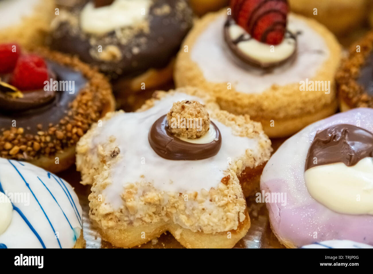 Various glazed doughnuts with chocolate, strawberries and hazelnut. Stock Photo
