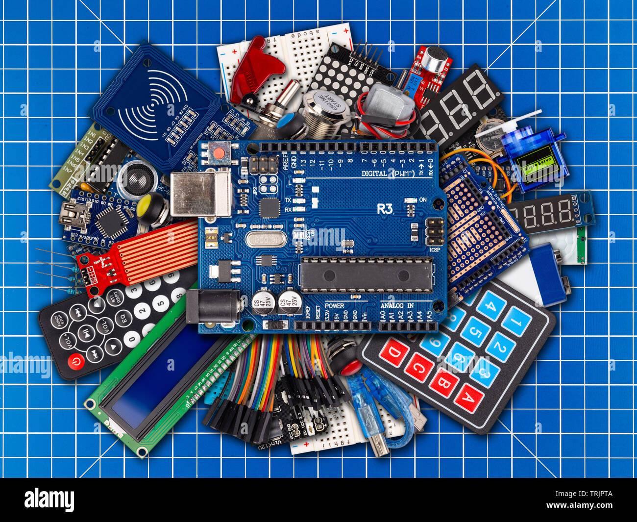 collage of microcontroller board display sensor button switches cable wire accessories and equipment on blue cutting matte workplace electronics conce Stock Photo