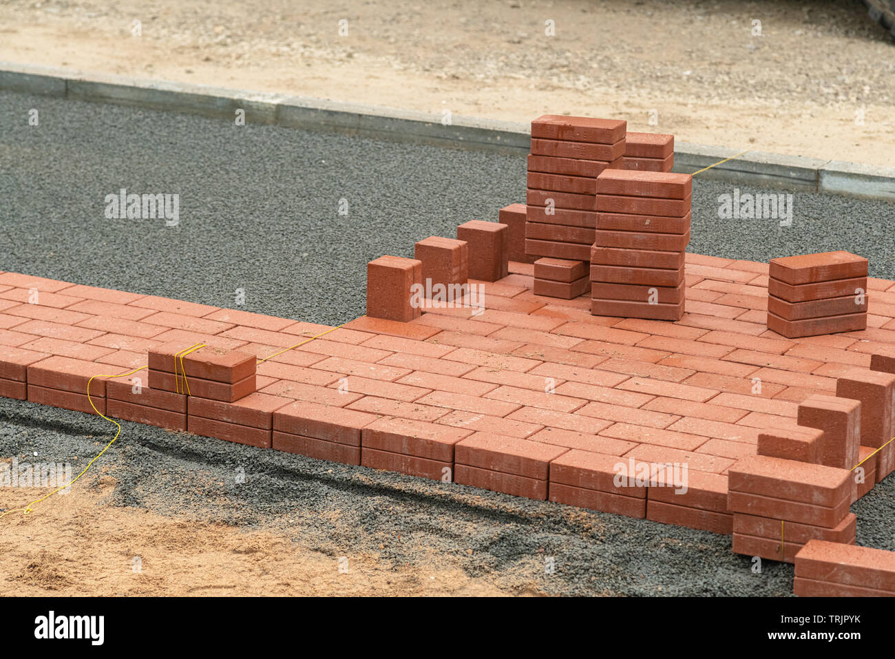 Laying red tiles on the sidewalk outdoors. Renovating paving in the street, construction, urban development Stock Photo