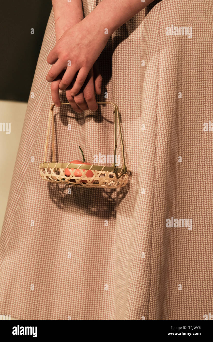 Model holding basket containing a satsuma at the Livia Tang Autumn Winter 2019 Presentation during London Fashion Week held at the Freemason's Hall. Stock Photo