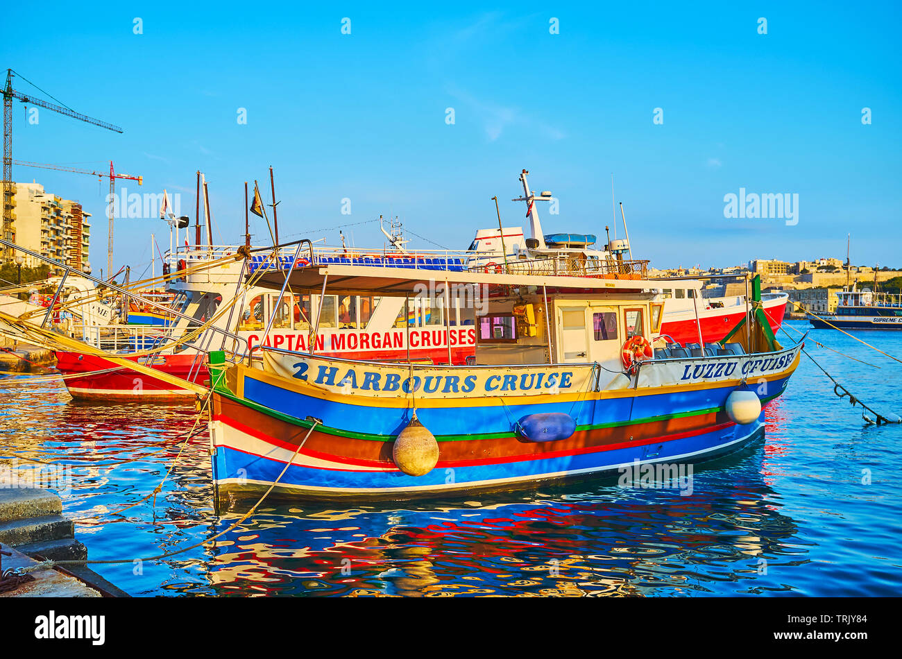 SLIEMA, MALTA - JUNE 19, 2018: The colorful pleasure boats moored at the shore of Resort and offer different trips around Valletta to the tourists and Stock Photo