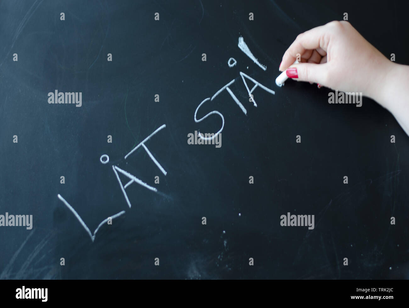 A black chalkboard with swedish Words for "Let stand" written on it ...