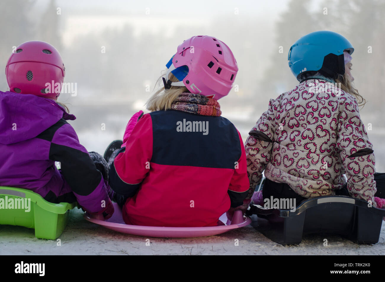 A group of four kids sledding down the hill on a snowy day Stock Photo