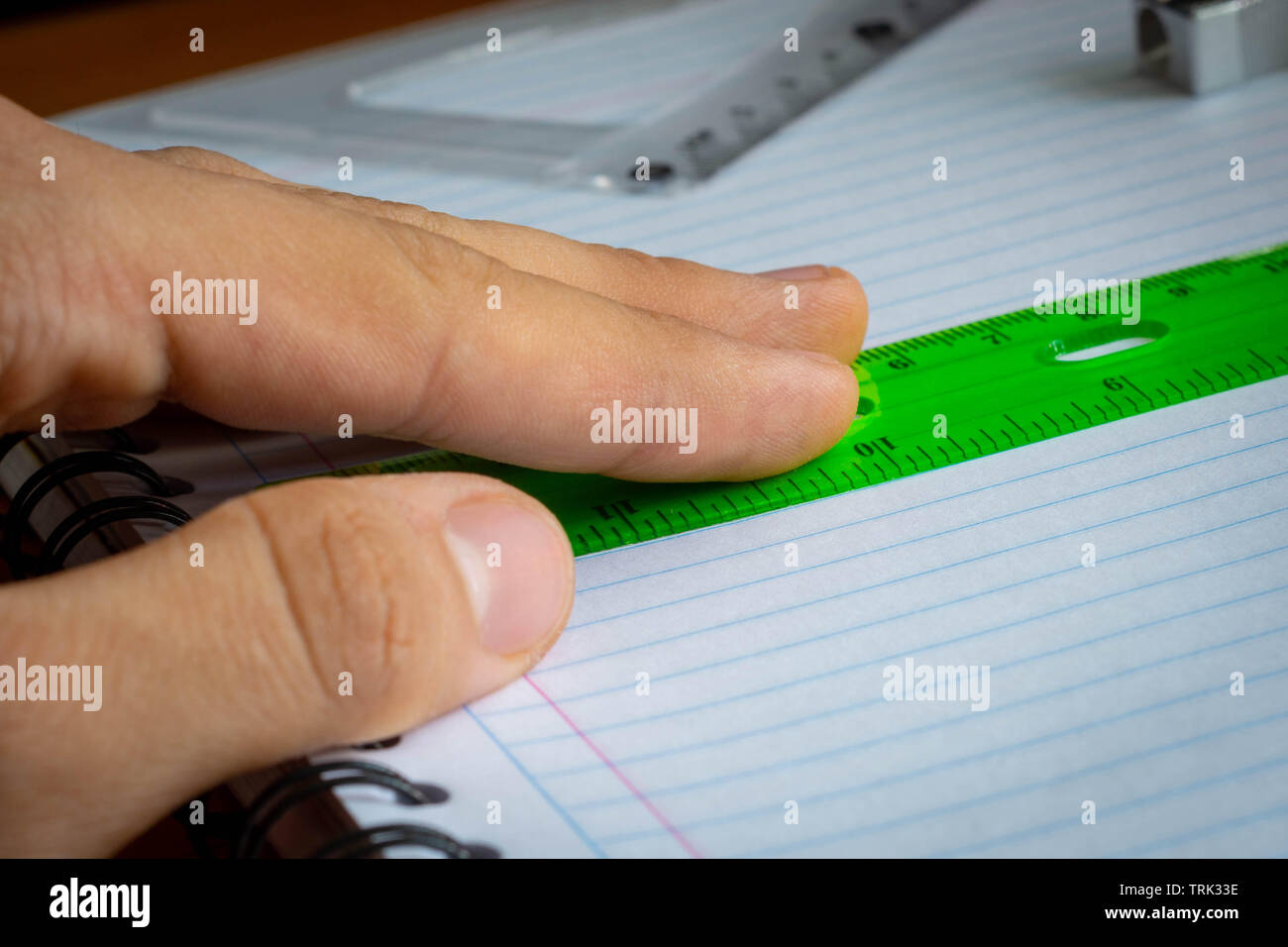 Hand holding green rule on a notebook close up Stock Photo