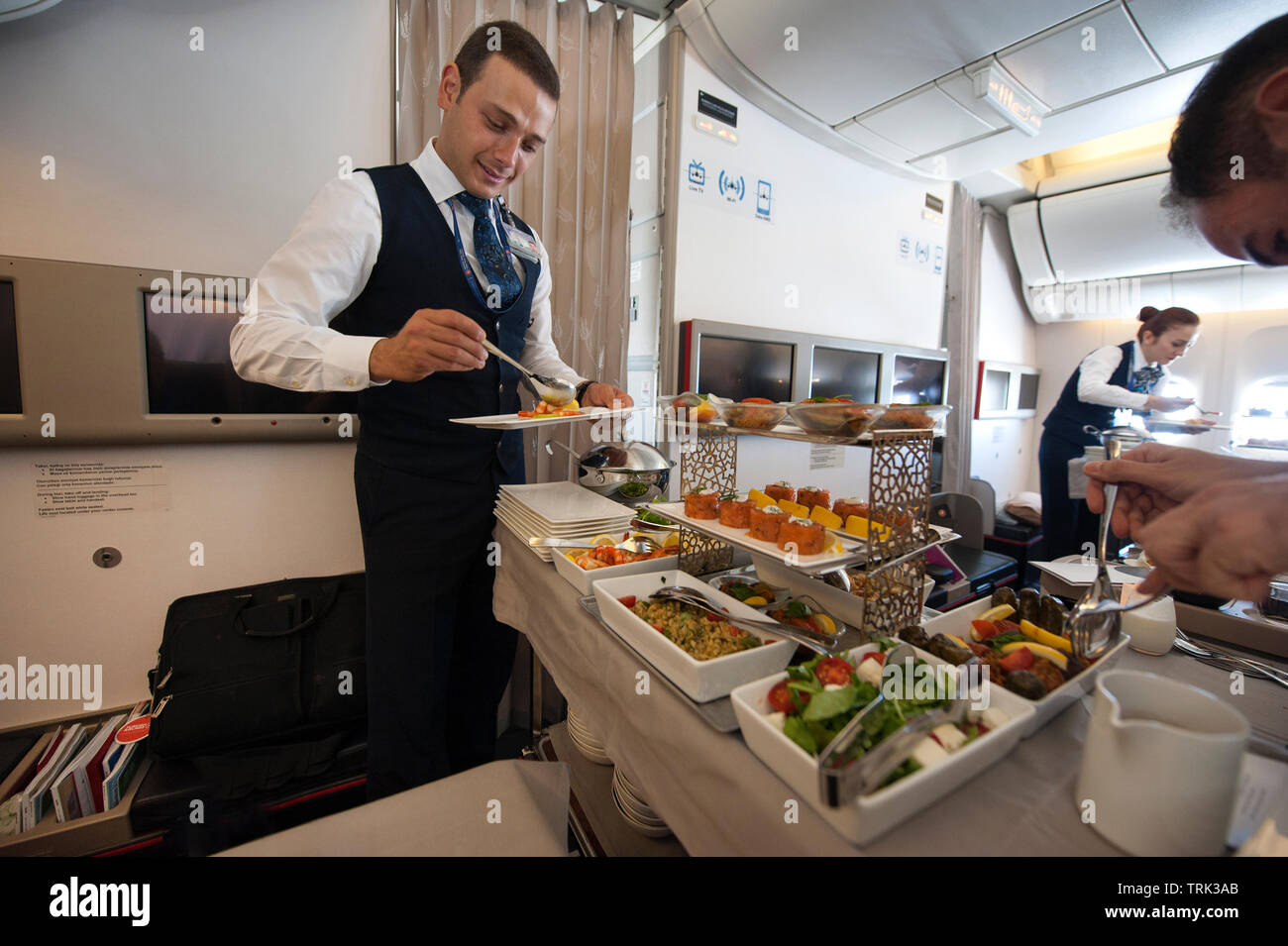 In flight crew serving gourmet dinner in business class section of Turkish airlines flight from Istanbul to Los Angeles, Stock Photo