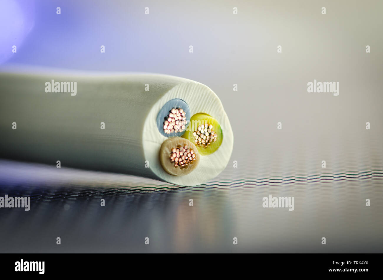 The cross section of the PVC cable consisting of three cores lies on a dark technological background Stock Photo