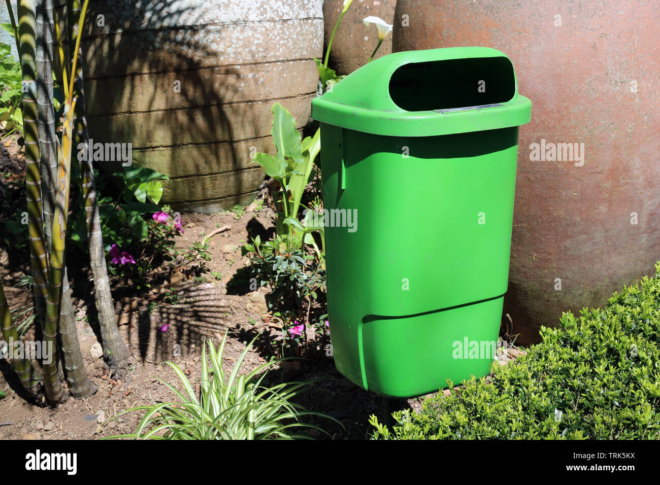 Green trash can photographed during a sunny day in a garden in Madeira