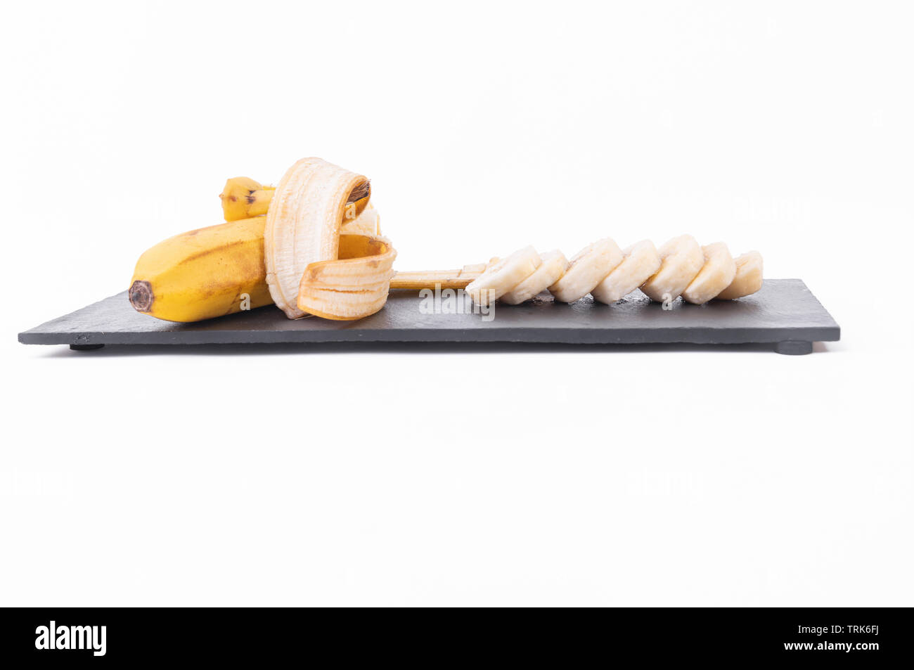 Sliced peeled banana, knife, chopping board. On white background Stock Photo