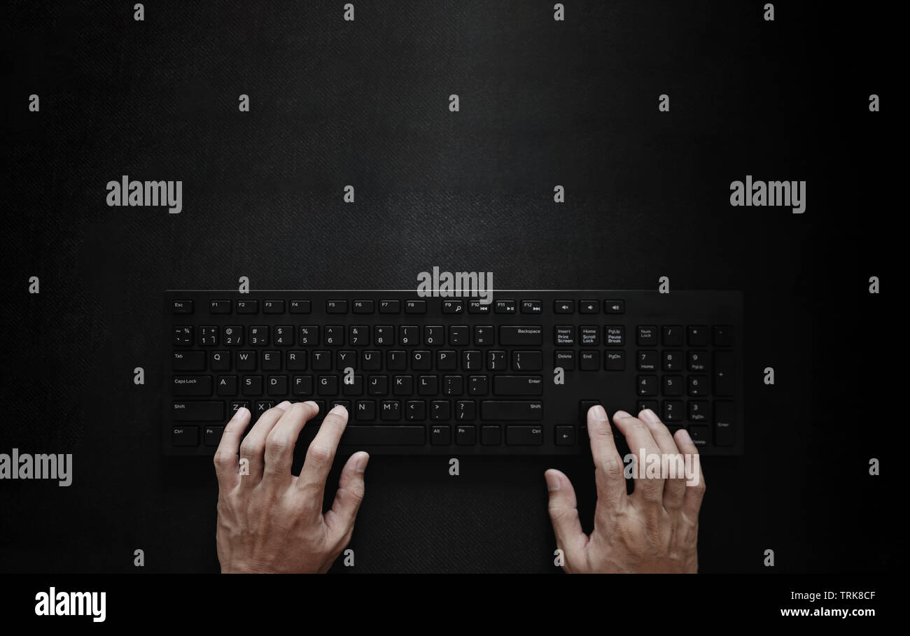 Top view, Hand typing computer keyboard on black background Stock Photo