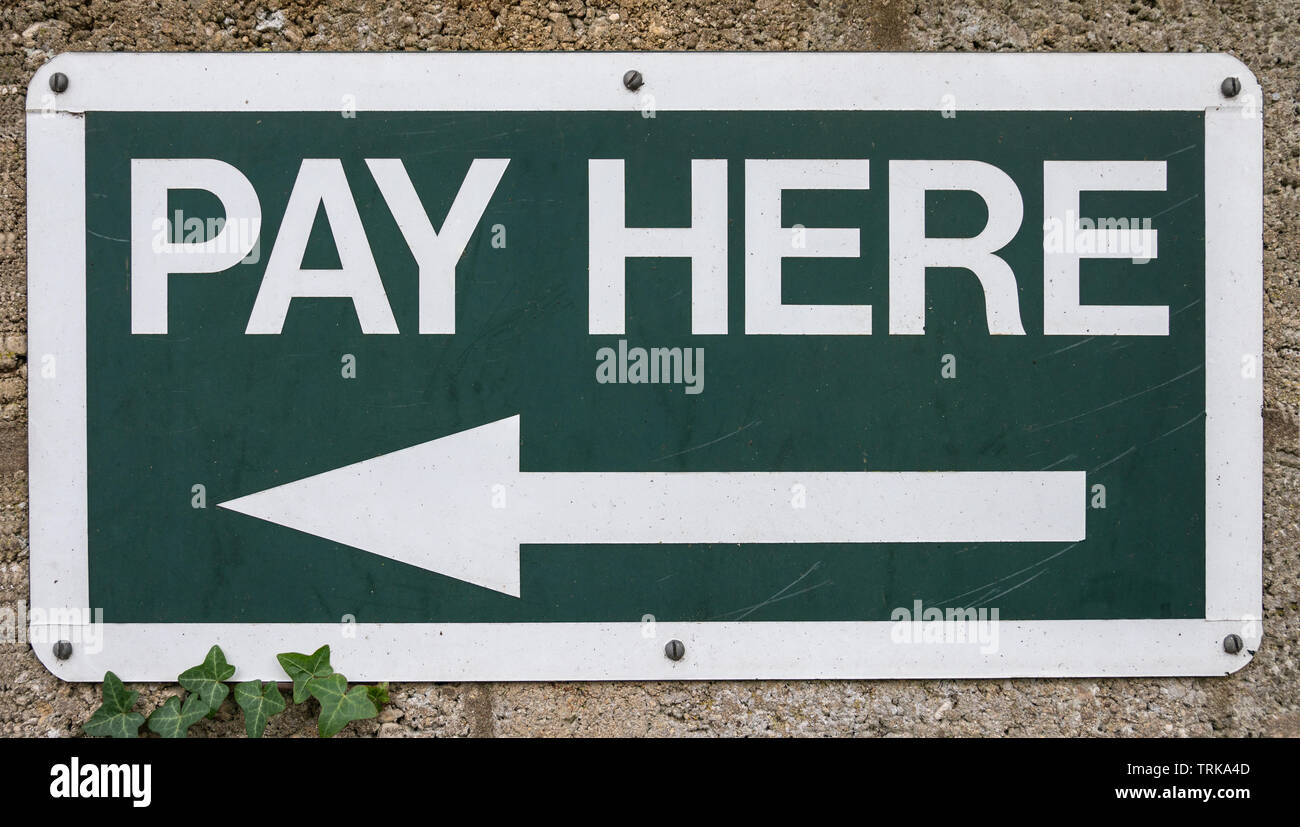 Pay Here sign - white text on dark green background Stock Photo