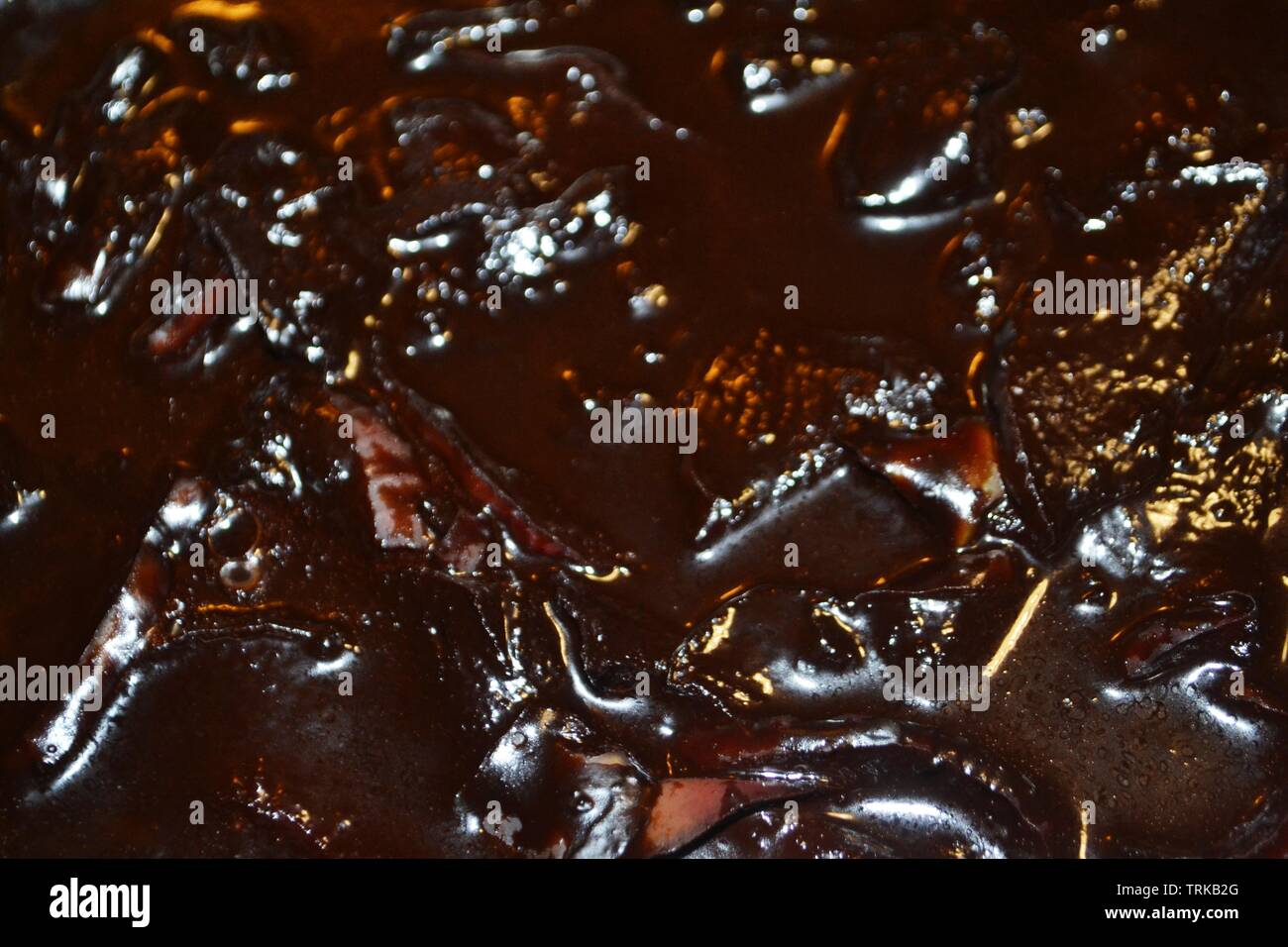 Blur background of dark brown liquid surface of chocolate apple slices jelly dessert. Stock Photo