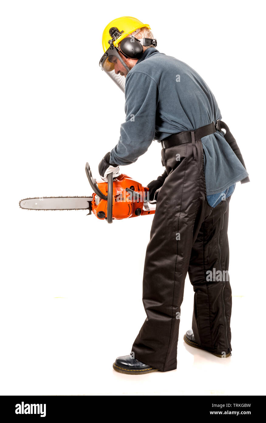 Man in safety gear demonstrating how to hold a chainsaw safely Stock Photo