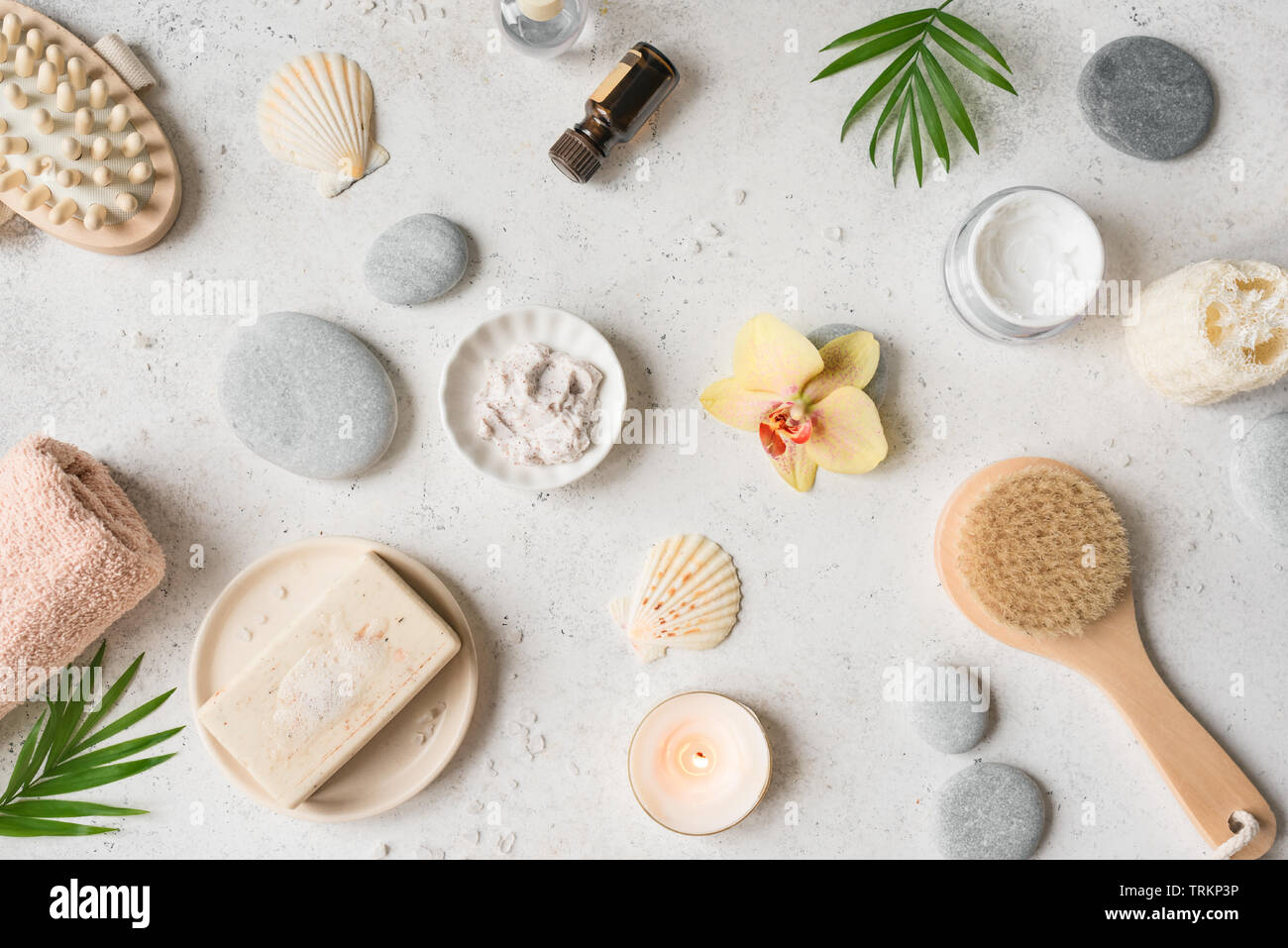 Spa concept, flat lay on white stone background, palm leaves, flower, candle and zen like grey stones, top view. Stock Photo