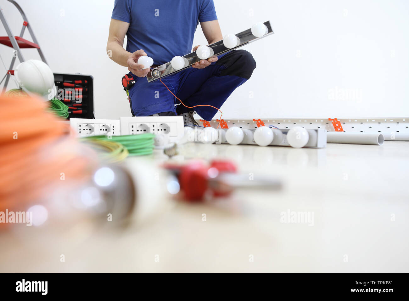 electrician at work installing lamp, with bulb in hand, install