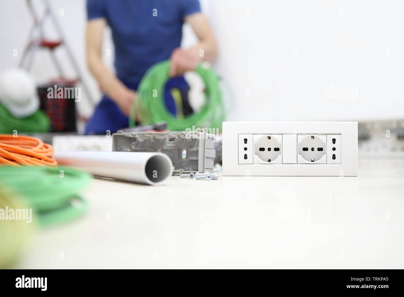 electrician at work with bundle of cable in hand, install socket