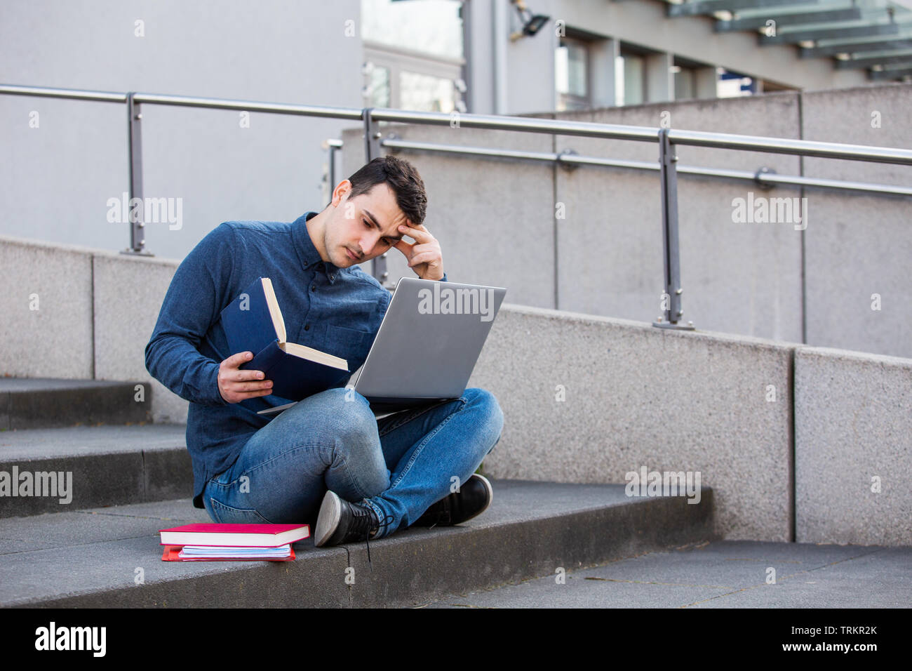 Stressed student preparing for an exam in campus area sitting on university stairs. Student man with laptop, sitting on university stairs. Technology, Stock Photo
