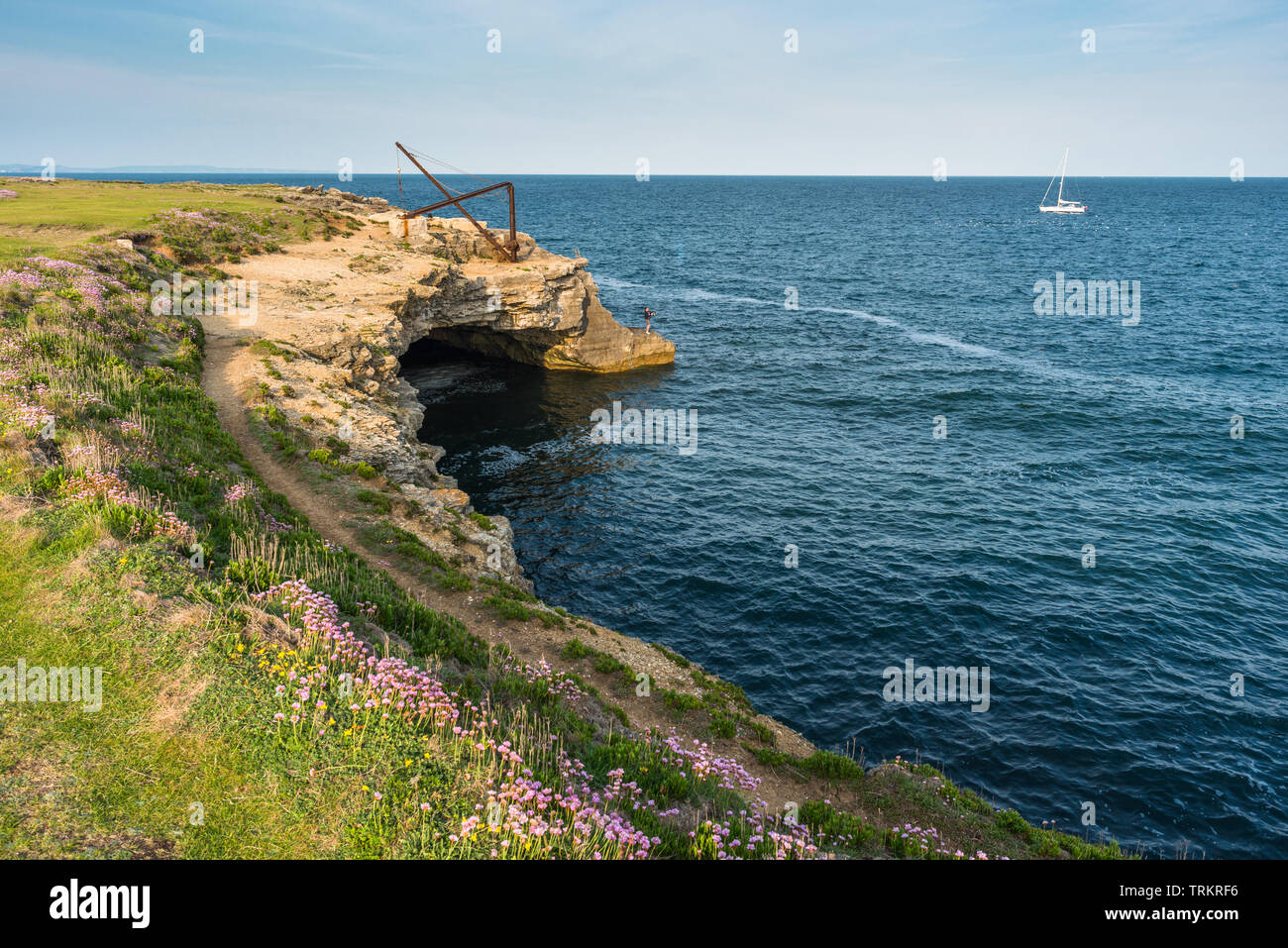 Disused Quarry lighting crane or hoist over a sea cave at Portland Bill on the Isle of Portland, Jurassic coast of Dorset, England, UK. Stock Photo