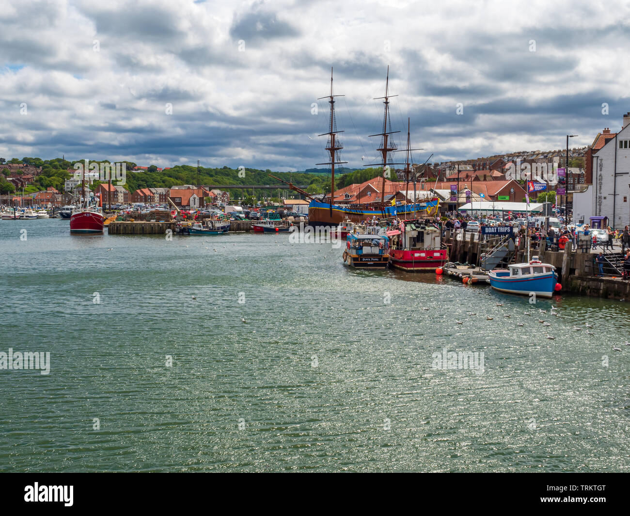 Whitby Harbour with Tall Sailing ship moored alongside modern fishing boats, as well as a tourist destination its also a working fishing port Stock Photo