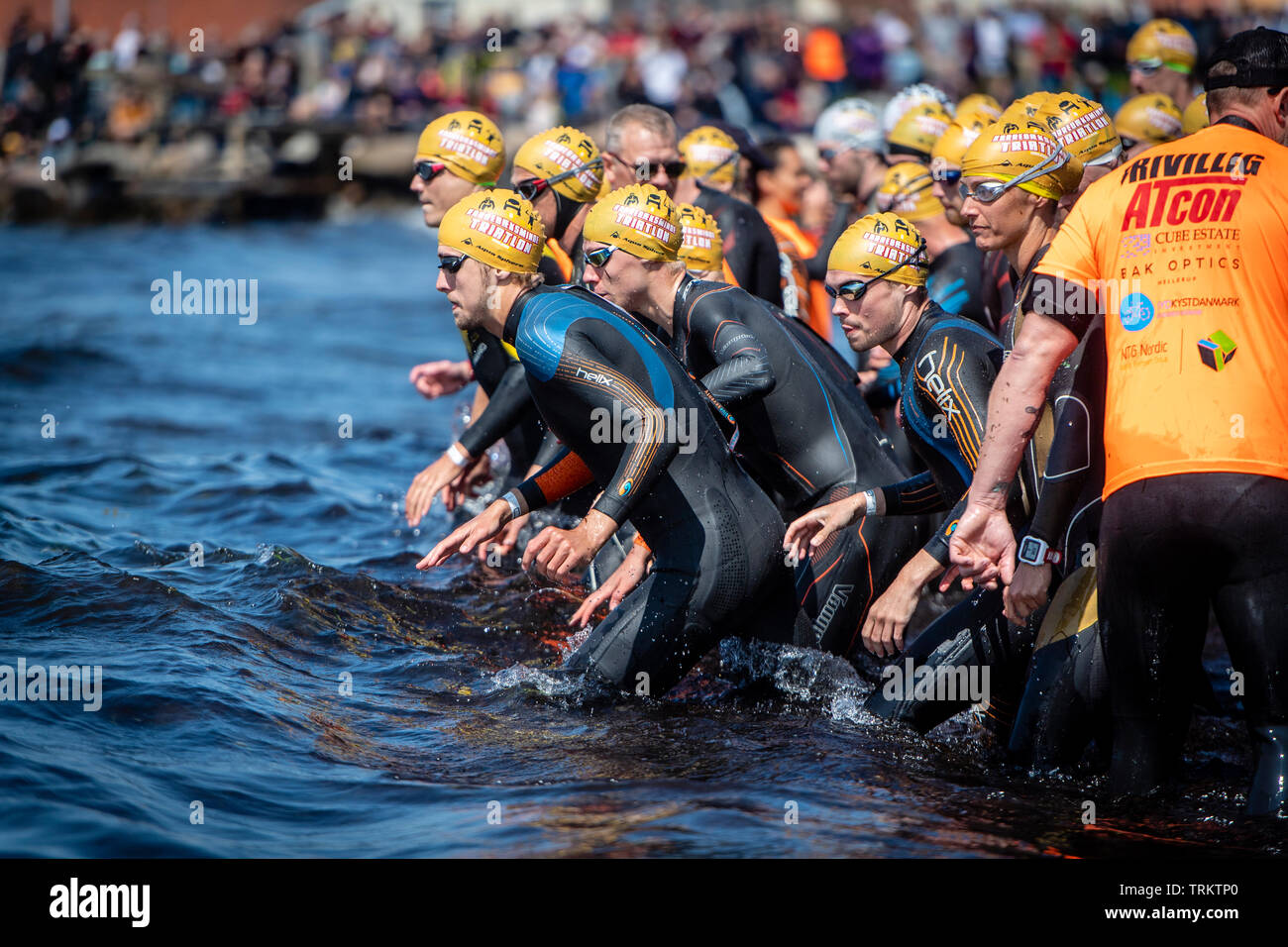 Large groups of triathlon contenders about to run into the sea during the Karrebæksminde Triathlon in Denmark. The participants are wearing wetsuits Stock Photo