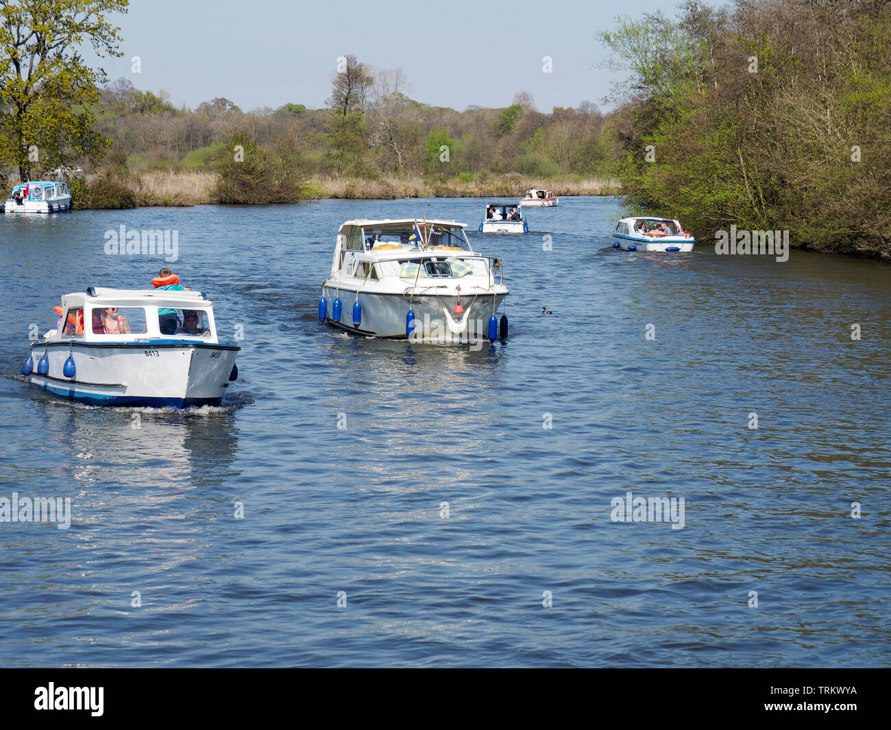 Motor cruisers and day boats enjoy a sunny day on the River Bure near Wroxham on the Norfolk Broads. Stock Photo