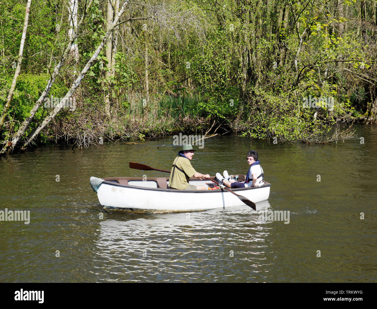 Enjoying the Norfolk Broads the quiet way this rowing boat is navigating the River Bure near Wroxham. Stock Photo