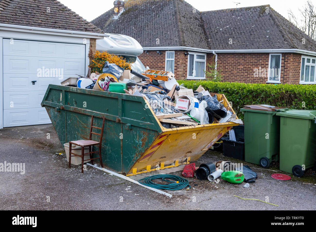 A full rubbish skip on a house driveway. Stock Photo