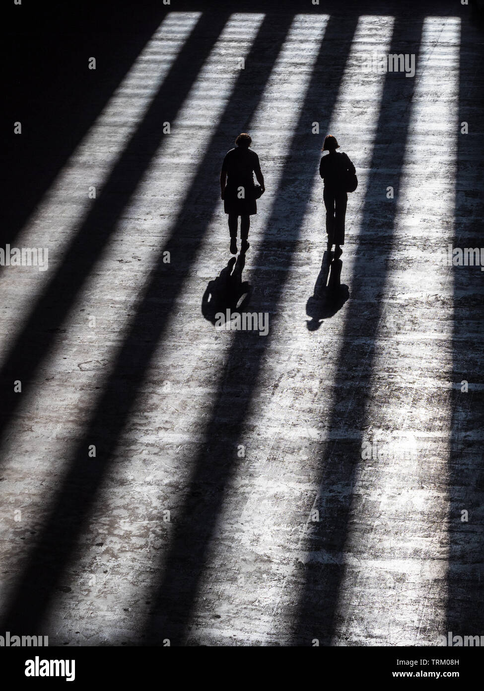 Tate Modern Art Gallery - shadows fall on people walking towards the gallery exit Stock Photo