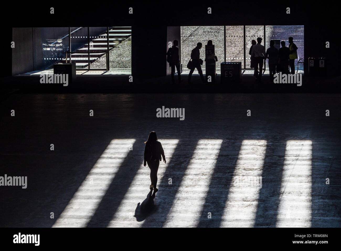 Tate Modern Art Gallery - shadows fall on people walking towards the gallery exit Stock Photo