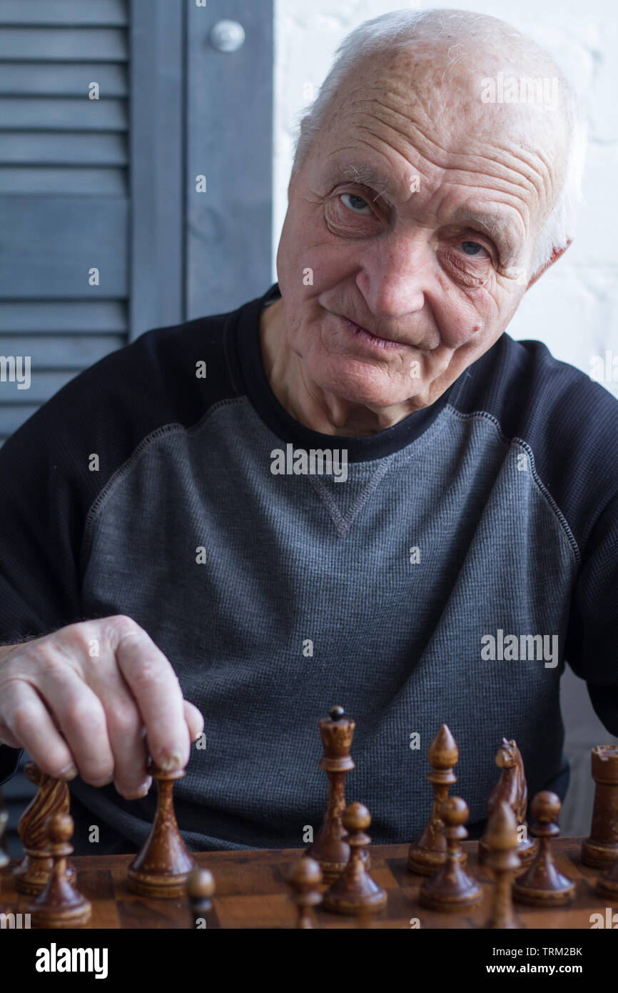 Smiling grandfather having idea about next chess move Stock Photo by  ©Dmyrto_Z 165212578