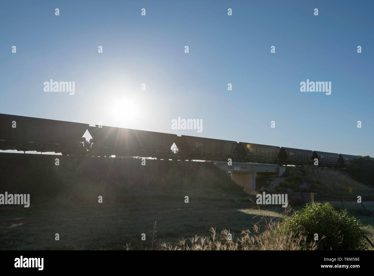 Silhouetted rail freight cars near Gunnedah carry coal to the port at Newcastle from mines in the upper Hunter Valley in New South Wales, Australia Stock Photo