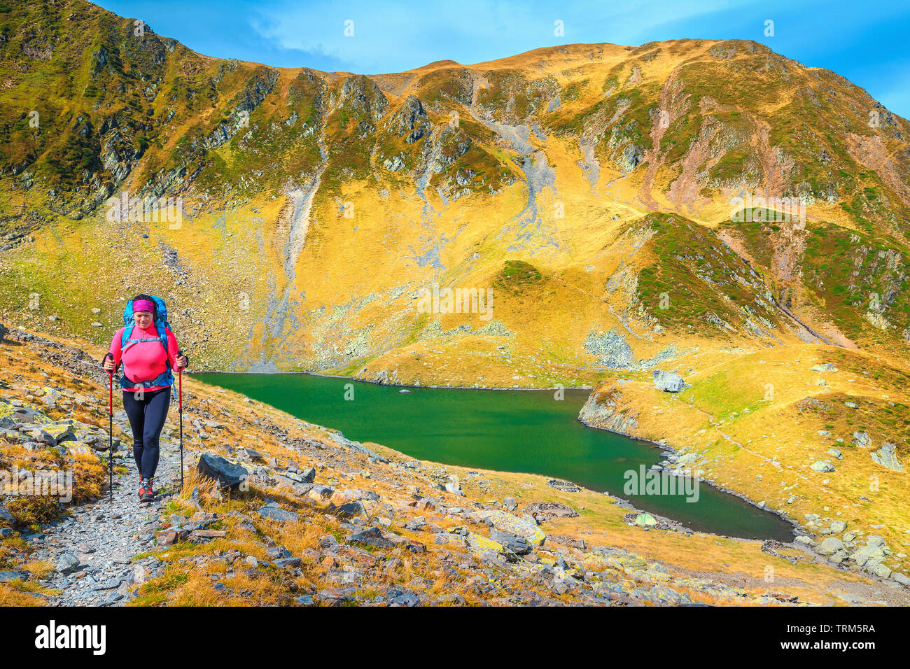 Cheerful sporty hiker woman with backpack on alpine hiking trails, Fagaras mountains, hiking and travel concept, Carpathians, Romania, Europe Stock Photo