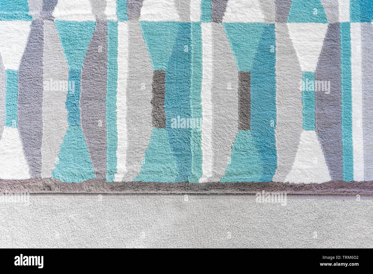 Background graphic, top view of a geometric rug with blue and grey color patterns, on top of a beige carpet, as a design element in home decor. Stock Photo