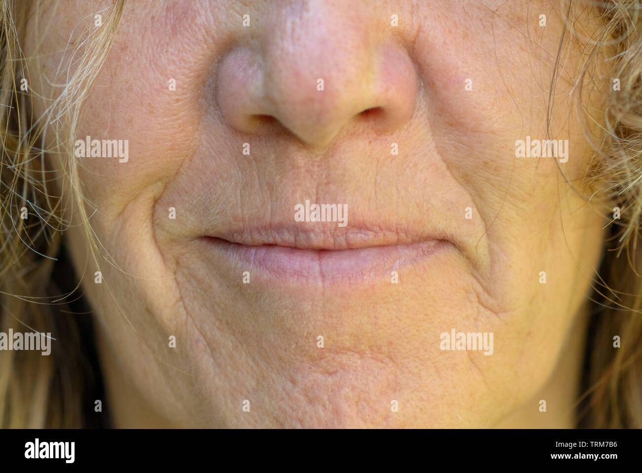 Close up on the mouth, nose and lips of a smiling mature woman showing the effects of ageing on the skin Stock Photo