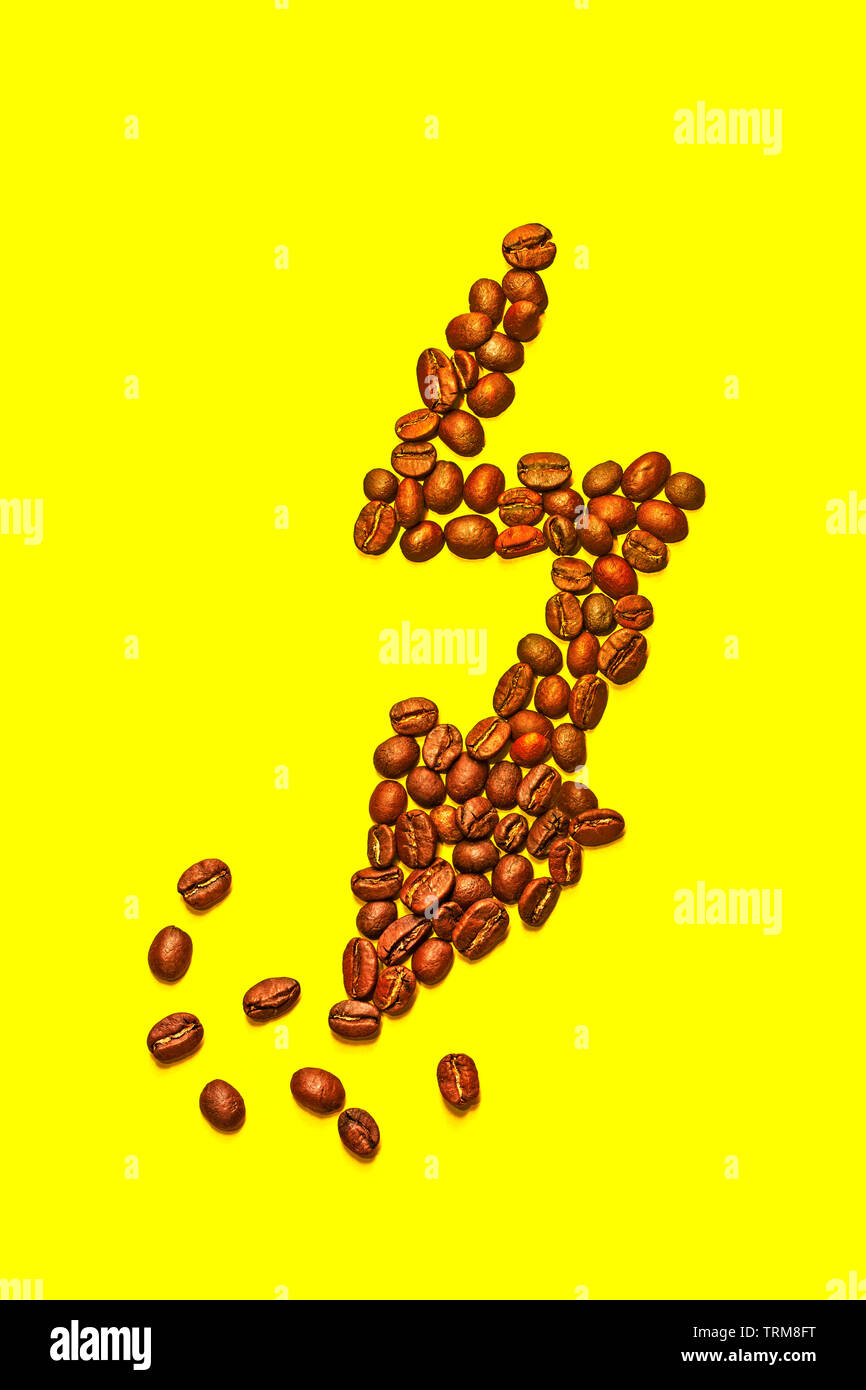 Isolated lightning shape made with coffee beans. Symbol of a superpower with the yellow background and copy space. Stock Photo