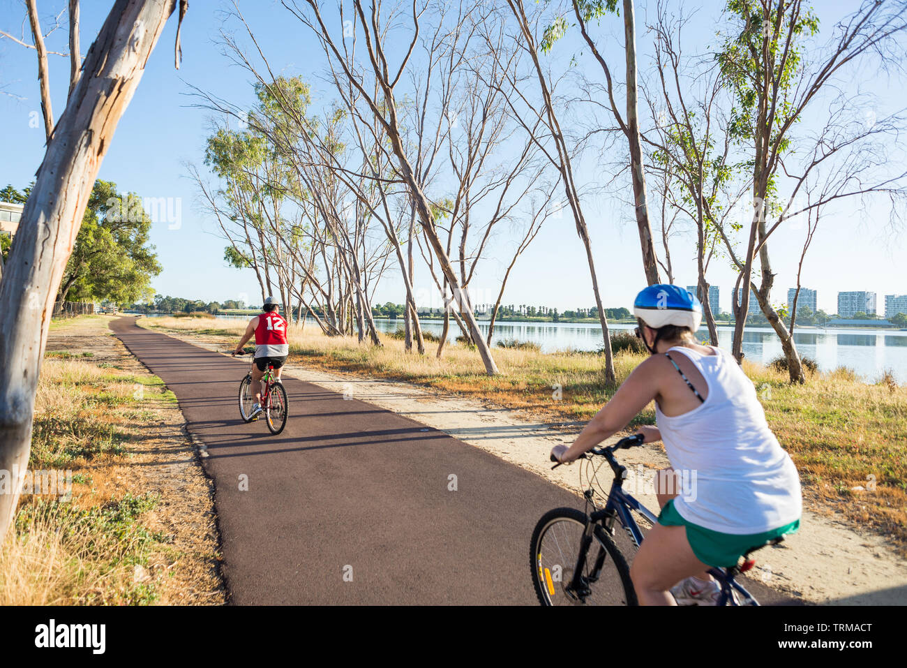 Two cyclists ride along the Principal Shared Path (PSP) bike lane beside the swan river in Perth, Western Australia Stock Photo
