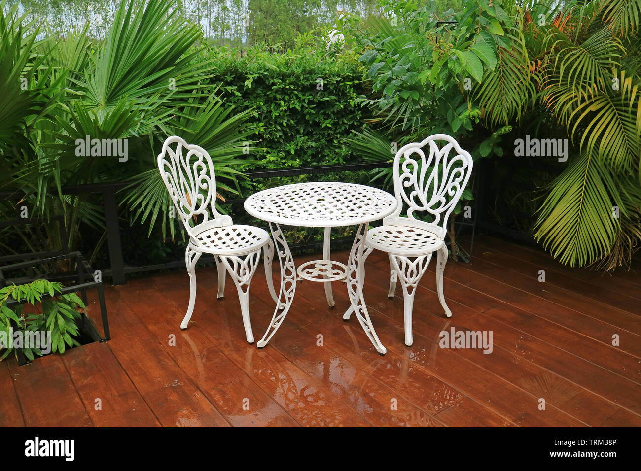 Empty white wrought iron garden tea table and chairs in the patio after  rain Stock Photo - Alamy