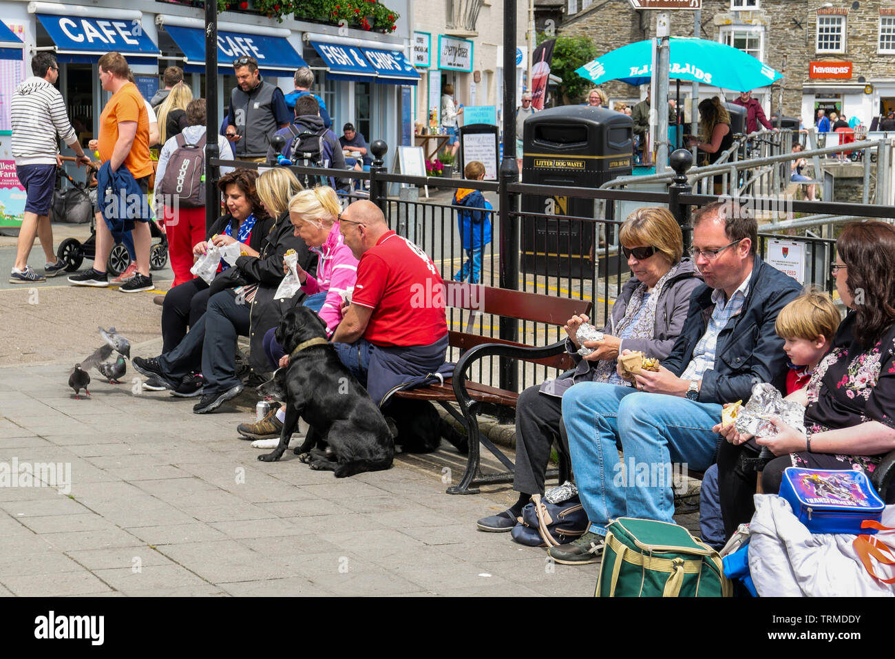 Padstow, England UK: Tourists snacking on benches by the harbour. Stock Photo