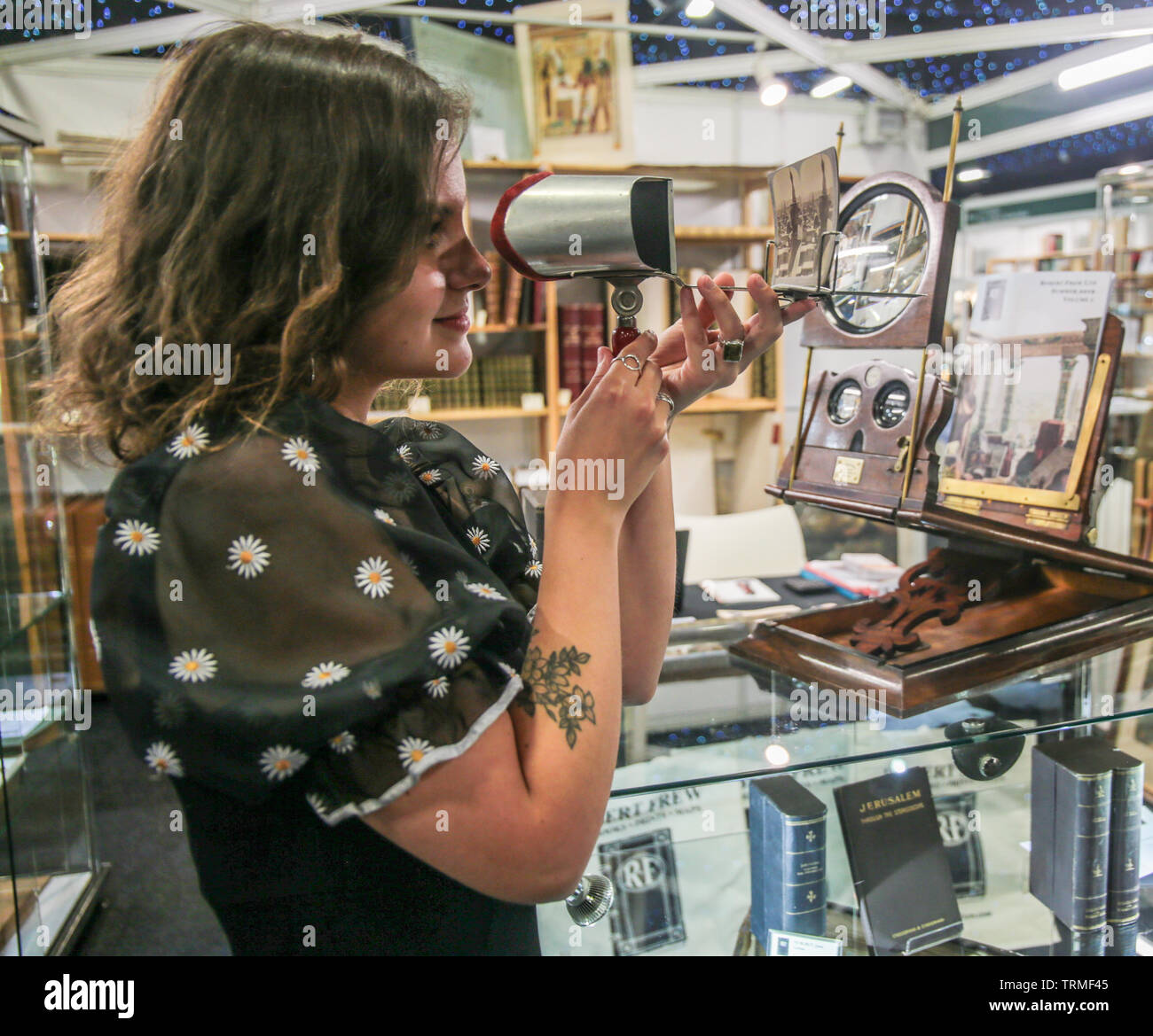 London, UK. 09 th June, 2019. Giulia from Italy looking trough a stereoscope i,device for viewing a stereoscopic pair of separate images, depicting left-eye and right-eye views of the same scene, as a single three-dimensional image shown by Robert  Frew Ltd at The London's  First Rare Book Fair, . Paul Quezada-Neiman /Alamy Live News Stock Photo
