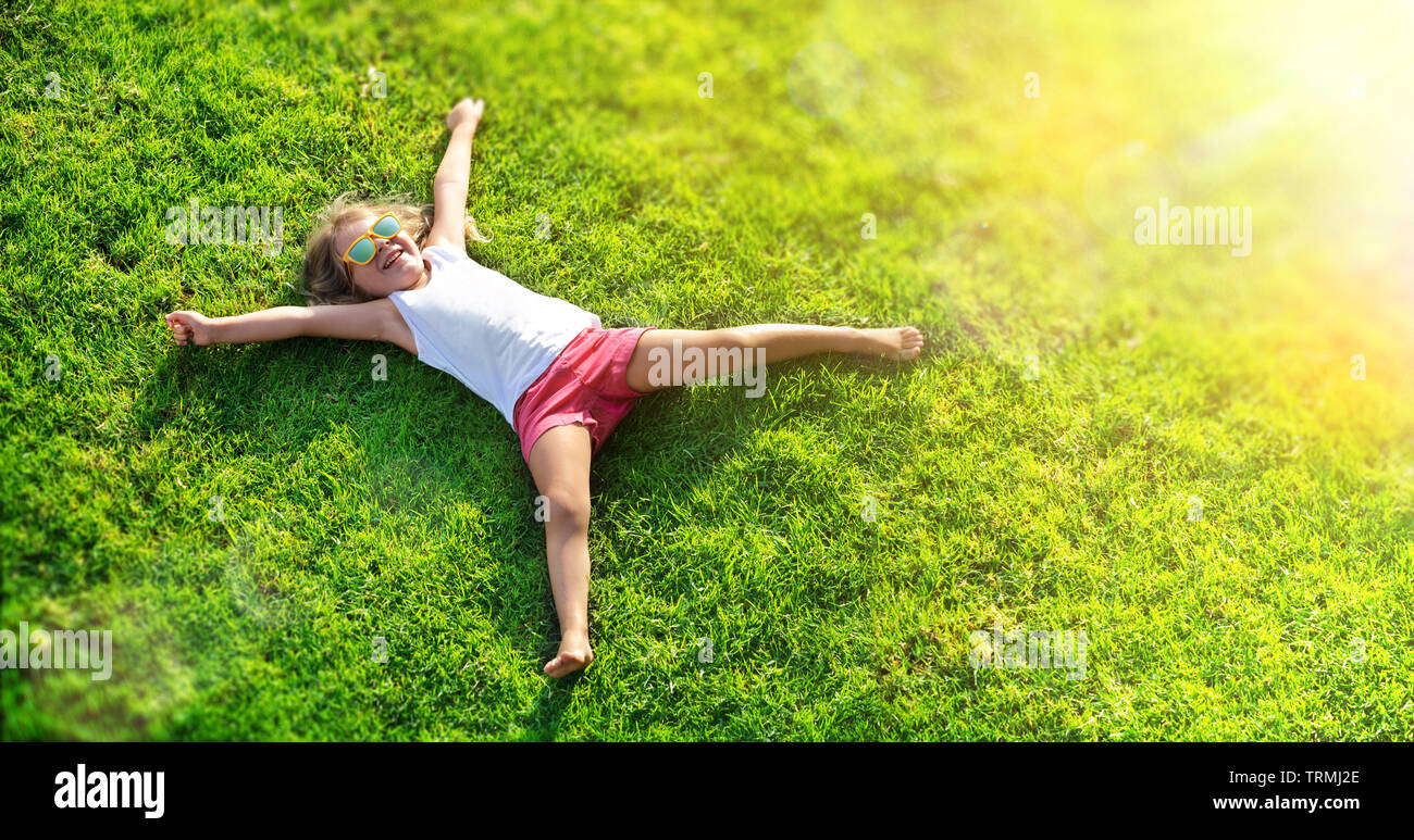 Smiling Little Girl Lying On Grass Meadow Stock Photo