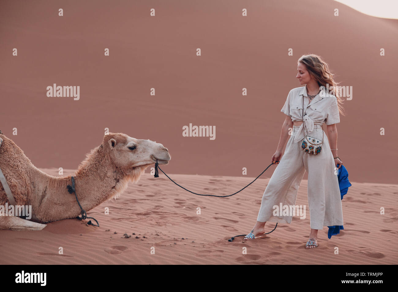 Caucasian young woman in linen clothes with camel in desert Stock Photo -  Alamy
