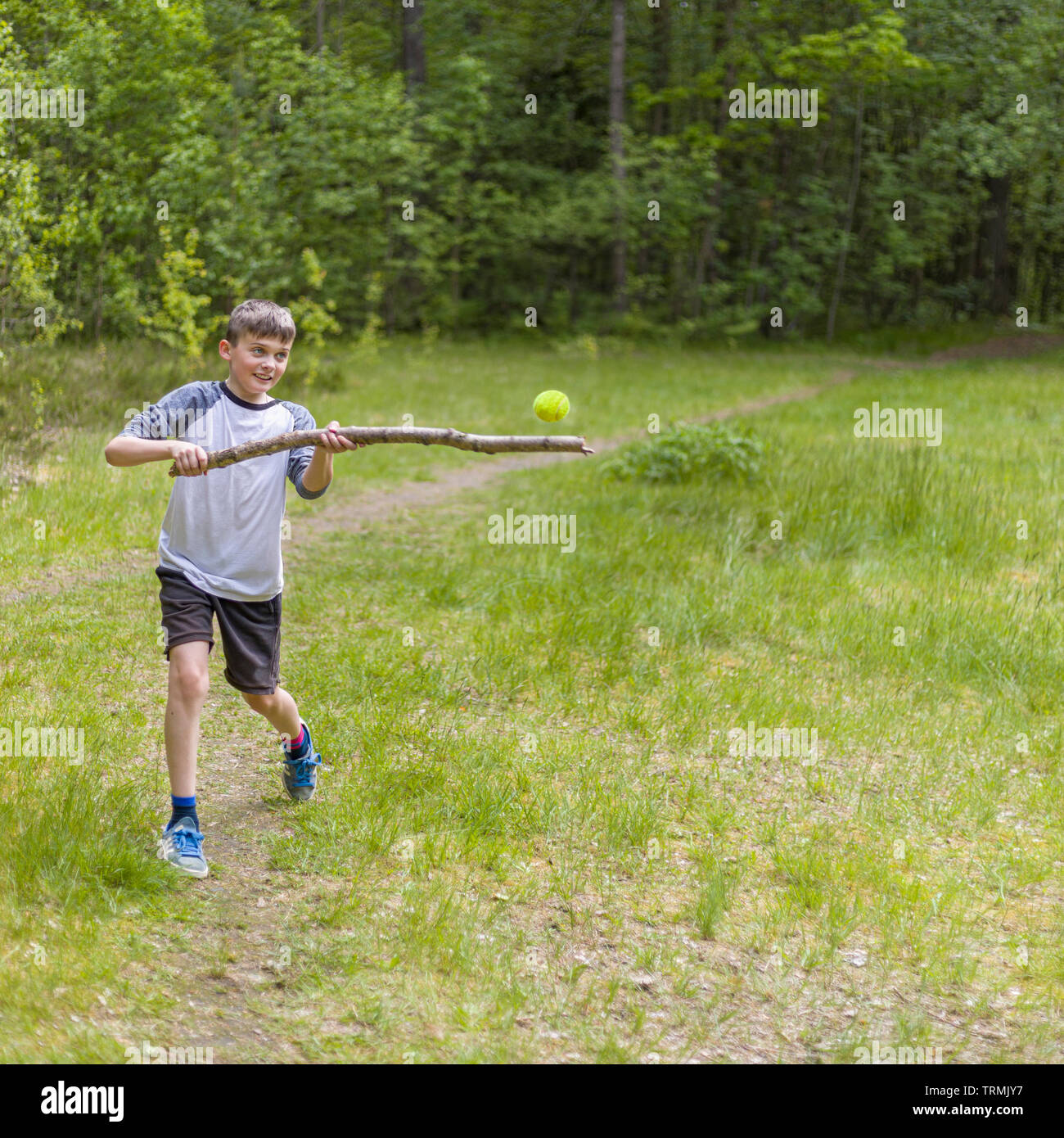 Young boy playing baseball or rounders hitting tennis ball with