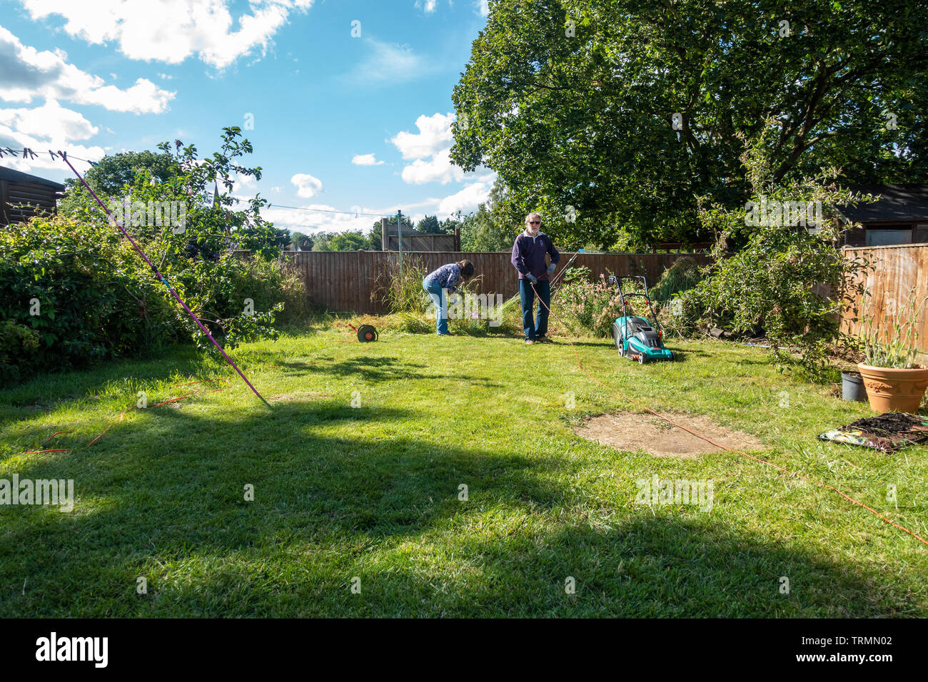 A retired couple doing gardening on a sunny day with blue sky in early summer. Stock Photo